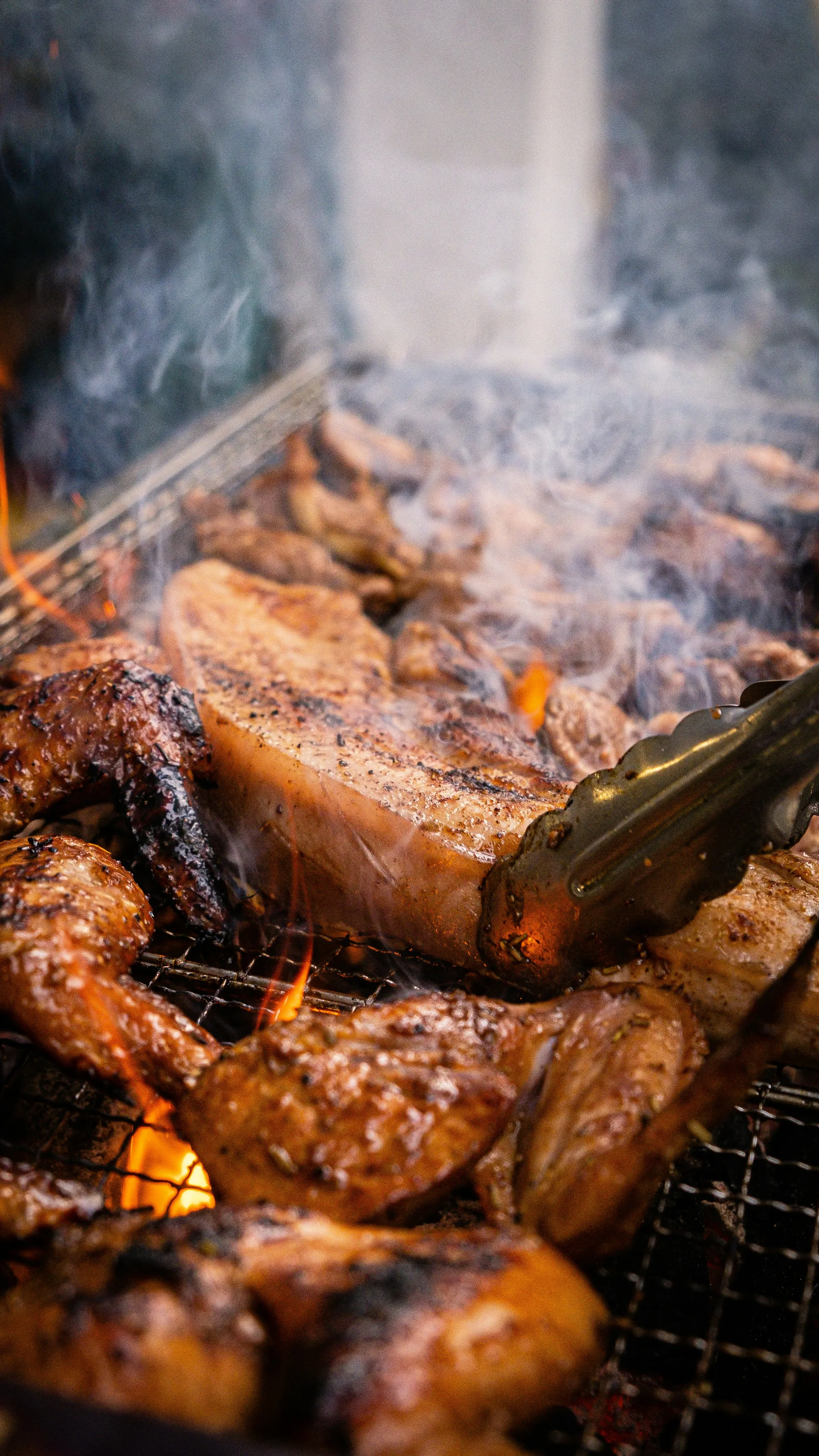 Carnes e frango na grelha, com chamas e fumaça